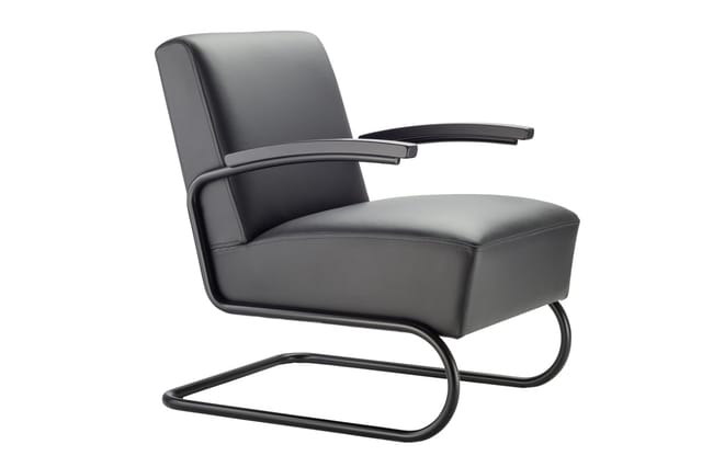 Grijze leren loungefauteuil met zwarte metalen buisvormige onderstel en gebogen armleuningen.