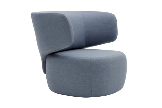 Grijze fauteuil met ronde zitting en ergonomische rugleuning met cylindrische kussen, stofbekleding.