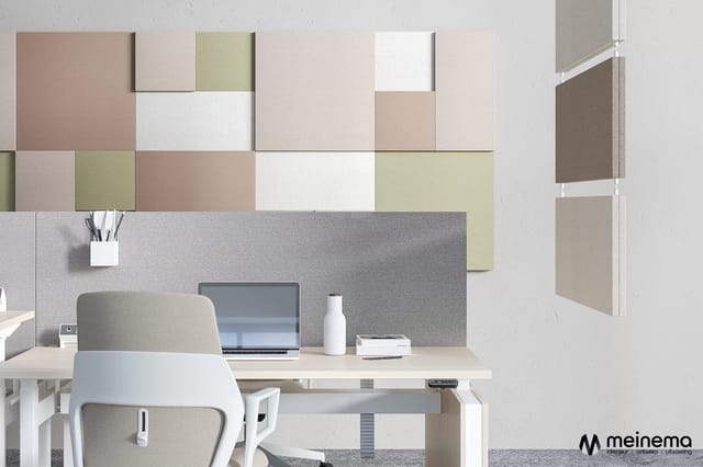 Modern kantoor met grijs akoestisch paneel, witte bureau met laptop, grijze ergonomische stoel en kleurrijke muurtegels in be