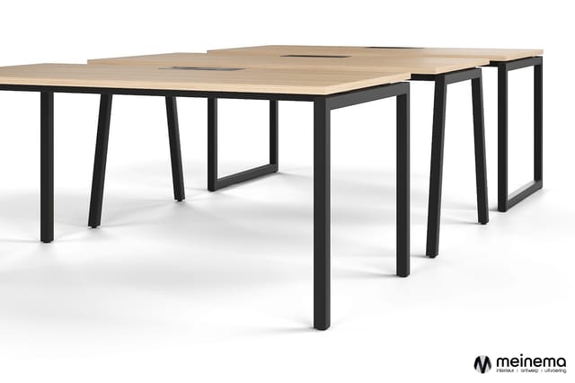Vergadertafel met licht houten blad en zwart metalen frame, modulair opgesteld in L-vorm met meerdere werkplekken.