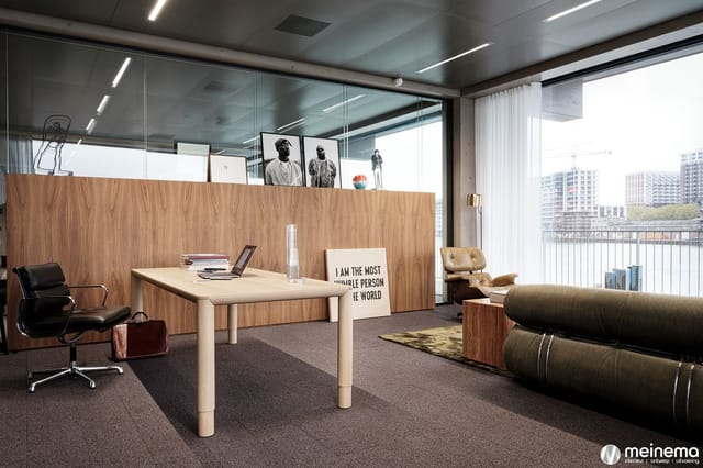 Kantoor met houten wand, lichte tafel, zwarte bureaustoel, beige fauteuil, zwarte loungeset en tekstbord "I AM THE MOST HUMBL