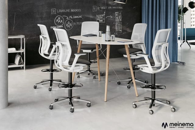 Moderne kantoorruimte met witte ergonomische bureaustoel op wielen rond een wit tafelblad met houten poten. Zwart memobord op