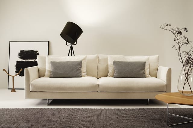 Moderne cremekleurige loungeset met twee zitplaatsen, grijze kussens, metalen poten, in minimalistisch interieur met grijs ta
