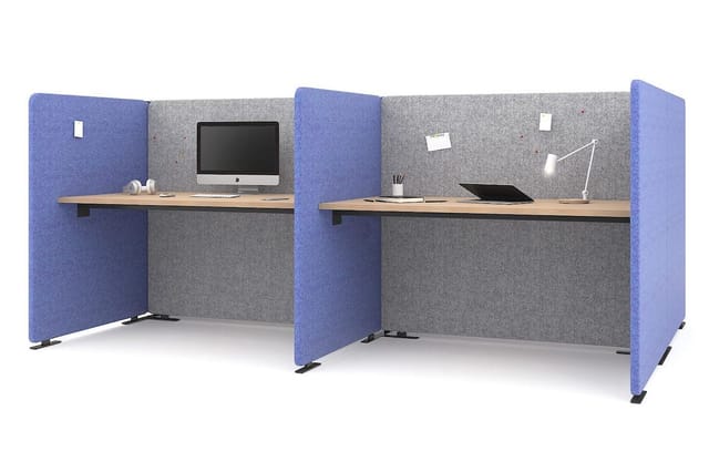 Twee akoestische werkplekken met blauwe en grijze geluidswerende panelen, houten werkbladen en bureauapparatuur.
