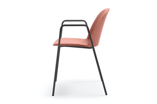 Bureaustoel met roze/terracotta gepolsterde zitting en rugleuning, zwart metalen frame met armleuningen, tegen witte achtergr