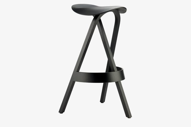 Zwarte houten barstoel met ergonomisch gevormd zitgedeelte, X-vormig frame en voetsteun.
