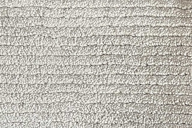 Grijsbeige akoestische wandbekleding met gestructureerd oppervlak in horizontale rijen.