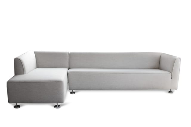 Grijze hoekbank met chaise longue links, chromen poten, modern design op witte achtergrond.