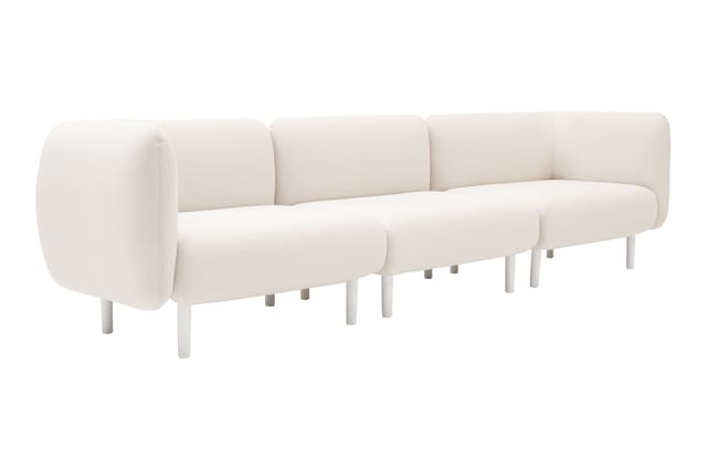 Crème witte modulaire sofa met afgeronde vormen, cylindrische armleuningen en witte poten tegen witte achtergrond.
