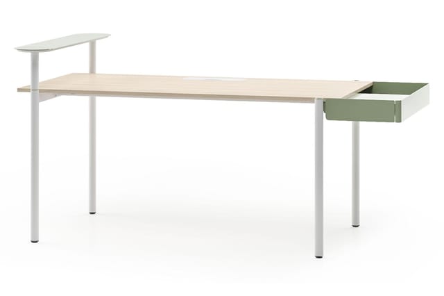 Strak bureau met lichte houten blad, witte poten, groen-grijs ladekastje op rechts en verstelbare tafelpanelen links.