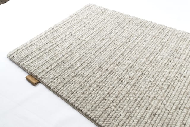 Beige geweven tapijt met ribtextuur en houten details, zicht vanaf bovenkant op witte achtergrond.