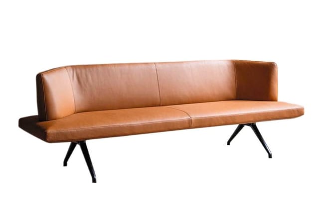 Bruine leren lounge bank met rugsteun, zwarte spreidpoten, minimalistisch design.