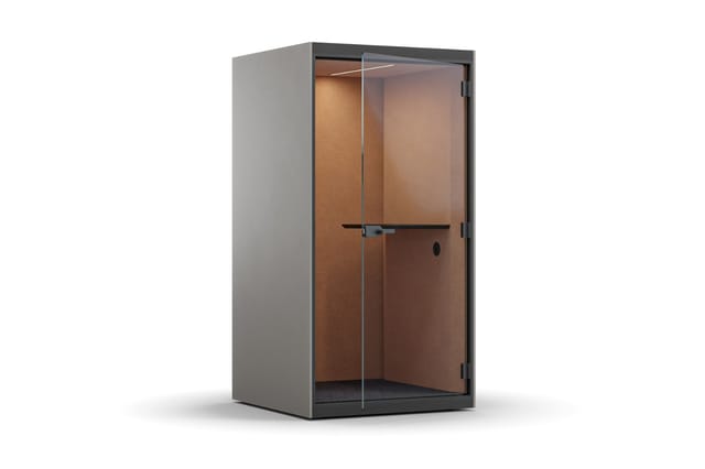 Akoestische belcel met grijze aluminium frame, glazen deur en bruine akoestische wanden, staande opstelling tegen witte achte