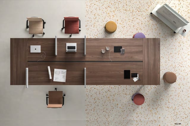 Bovenaanzicht van een werkplek met bruin houten bureau, twee laptops, witte koptelefoons, drie gekleurde ergonomische stoelen