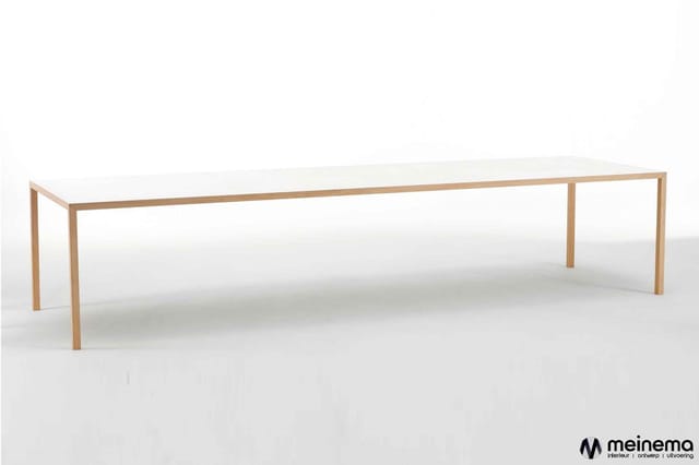 Lange rechthoekige vergadertafel met wit blad en houten frame in natuurlijke houtkleur, staande in heldere ruimte.
