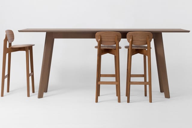 Houten bartafel met tafelblad in donkerbruin, twee bijpassende barkrukken met rugleuning en één losse barkruk links.