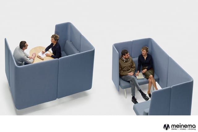 Twee blauwe akoestische belcellen met afgeschermde zitruimtes. Links twee personen bij ronde tafel, rechts twee personen op z
