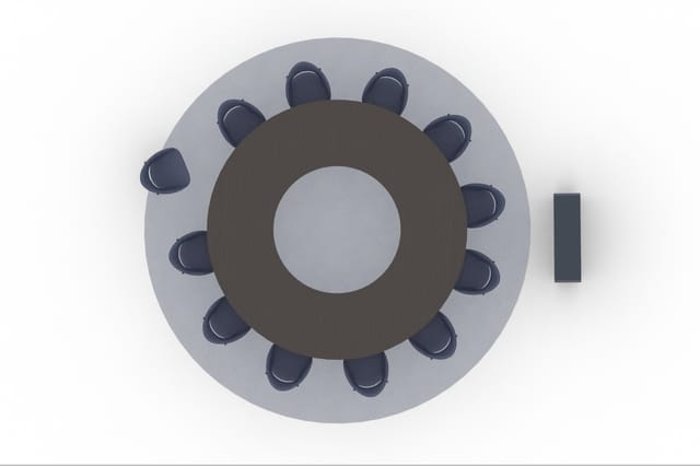 Bovenaanzicht ronde vergadertafel met donkerbruin blad en twaalf donkerblauwe bureaustoelen eromheen op grijs oppervlak.