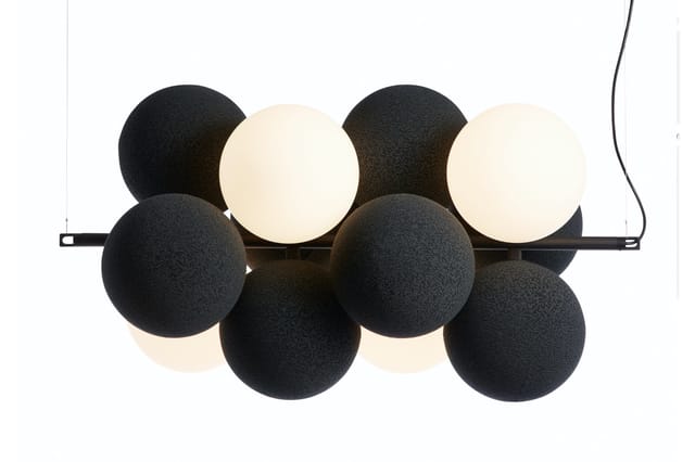 Hangende plafondlamp met zwarte en crème-witte bolvormige diffusers op zwarte montagestaaf.
