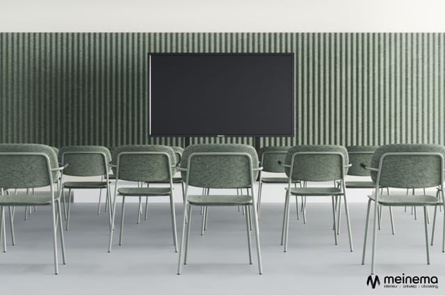 Rij grijsgroene stoelen met metalen frames in vergaderruimte met groen gestreepte wand en zwart scherm.