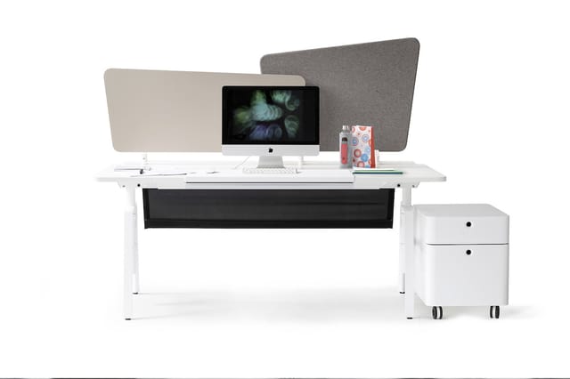 Witte bureau met zwarte kabelgoot, twee grijze akoestische schermen, iMac-monitor, rode objecten en witte ladeblok op wielen.