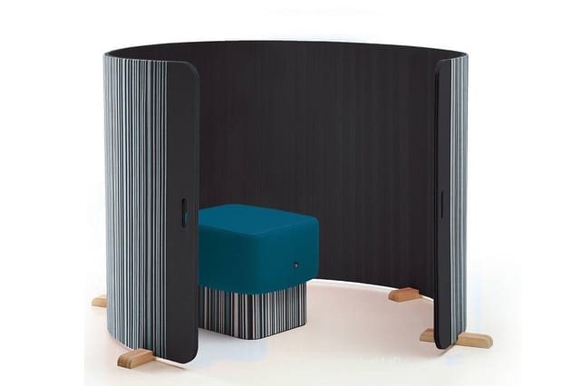 Akoestische afscherming met verticale latten in zwart en wit, houten voetjes, met turquoise zitpoef binnen de ruimte.